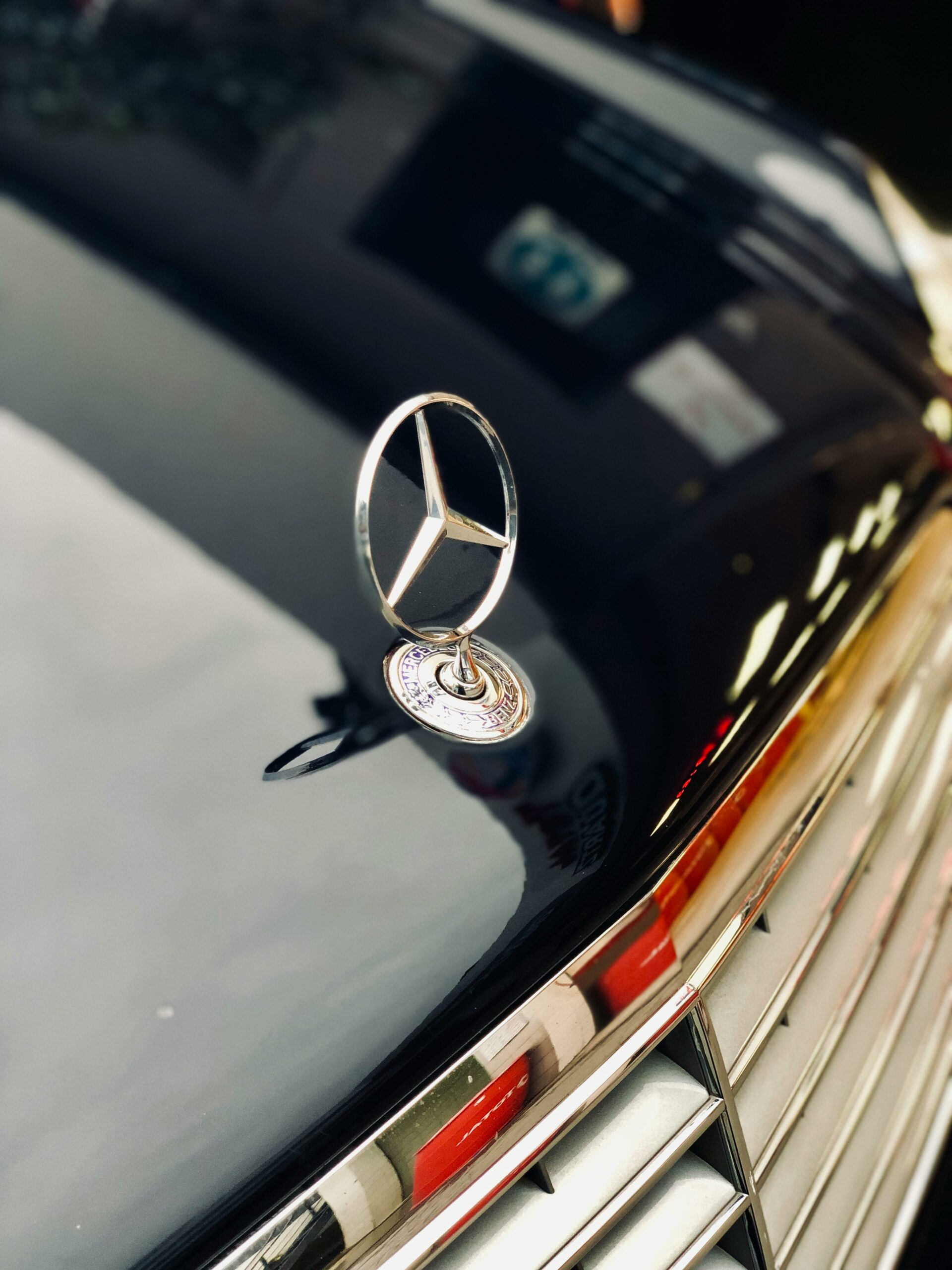 Glossy chrome Mercedes-Benz emblem on car grill, capturing elegance in Islamabad, Pakistan.